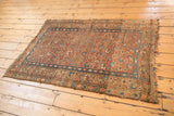 Kurdish Hamadan rug corner with blush and sky blue floral bouquet, tattered fringe, secure side.