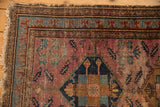 Vintage Malayer rug corner with worn raspberry field, tattered fringe, and pawn border.