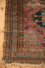 Worn corner of this vintage Malayer rug with tattered fringe, blue pawn border, and raspberry field.