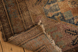 Malayer rug close-up showing exposed foundation, tattered fringe, and worn brown, blue, raspberry tones.