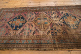 Vintage Malayer rug showing worn raspberry field, blue medallion, and unique pawn motif border.