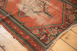 Tomato red vintage Hamadan rug corner with pawn borders and visible foundation wear.