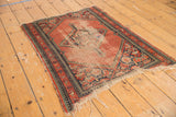 Vintage Hamadan rug corner: worn red field, reciprocating pawn motif border, tattered fringe.