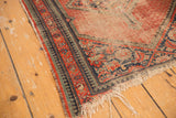 Worn red field, tattered fringe, and navy reciprocating pawn borders of a vintage Hamadan rug.