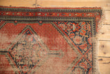 Vintage Hamadan rug corner: red and navy pawn borders, heavily worn field, tattered fringe.
