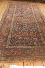 Antique Kurdish Bijar end, showing madder root red border, navy floral field, and tattered fringe.