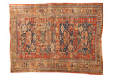Antique Caucasian Soumac carpet with navy medallions, red field, pinwheel motifs, and wave border.