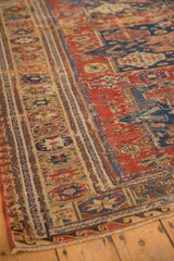 Antique Soumac carpet corner with red and navy geometric flat-weave wave border.