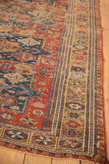 Antique Soumac carpet's geometric reciprocating wave border in red, navy, and gold.