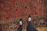Brick red vintage Heriz carpet with low, even pile, geometric floral patterns, and navy border.