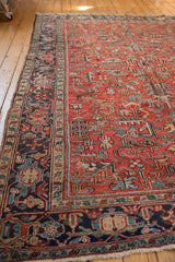 Vintage Heriz rug corner: low pile, brick red geometric florals, and navy border.