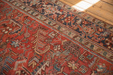 Detail of vintage Heriz rug's brick red field, geometric florals, navy blue border.