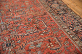 Vintage Heriz rug, brick red field displaying geometric leaves and navy blue border.