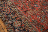 Navy blue geometric border contrasting with brick red field's serrated leaf motifs.
