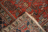 Heriz carpet's low pile, fringed end, and hand-knotted foundation showing even wear.