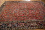Vintage Heriz rug detail showing brick red field, elongated serrated leaves, and navy geometric border.