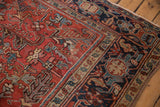 Vintage Heriz rug corner, brick red field, serrated leaf and geometric floral motifs, navy border.