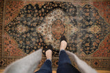 Traditional antique Farahan Sarouk rug: scalloped medallion, dark blue field, and faded low pile texture.