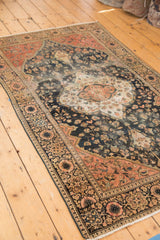 Antique Farahan Sarouk rug: navy scrolling floral field, blush border, and visible wear with color migration.
