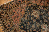 Antique Farahan Sarouk rug corner, dark blue scrolling florals and rose spandrel, with aged texture.