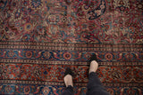 Ornate scrolling curvilinear floral design and navy blue border on a vintage Meshed carpet.