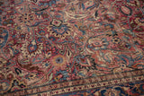 Scrolling curvilinear florals and botehs in cochineal red, navy, beige, with even wear and patterned border.