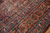 Ornate scrolling curvilinear floral motifs and botehs in cochineal red, navy blue, beige, showing even wear.