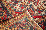 Vintage Heriz rug corner fold reveals Samovar border, serrated floral patterns in cherry red, ivory, navy.