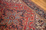 Vintage Heriz carpet's cherry red diamond starburst field and navy blue Samovar border.