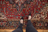 Vintage Heriz carpet in cherry red and navy with geometric patterns, a person's feet.