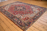 Vintage Heriz carpet corner, navy border's reciprocating samovar, red geometric field, low pile.
