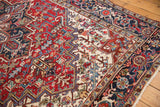 Vintage Heriz carpet detail: cherry red, navy blue geometric floral field, samovar motif border, low pile.