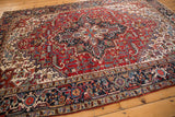 Corner of vintage Heriz rug, navy samovar border, cherry red geometric field.