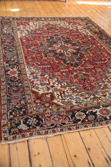 Vintage Heriz carpet featuring navy border's samovar motif and a cherry red geometric field.