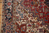 Vintage Heriz rug border with navy turtle motif, adjacent to an ivory and cherry red geometric field.