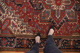 Geometric floral patterns of a Heriz rug in cherry red, navy blue, and ivory.
