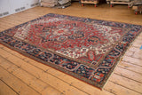 Vintage Heriz carpet's navy blue border, geometric floral motifs, and cherry red field.