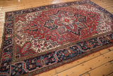 Cherry red geometric floral Heriz rug with patterned navy blue and ivory borders.
