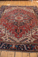 Corner of a Vintage Heriz carpet with cherry red, navy blue, ivory geometric floral motifs, and secure fringe.