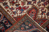 Vintage Heriz rug folded corner, showing red, navy, ivory geometric motifs, secured edge, and woven foundation.