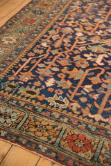 Vintage Persian Heriz carpet: navy field, intricate vinery, floral blossoms, and alternating border.