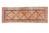 Distressed vintage Oushak runner with central diamond pattern in blush, raspberry red, and beige tones.