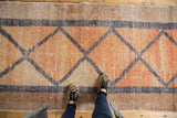 Distressed Oushak runner's geometric diamond pattern, faded raspberry, blush, beige colors.