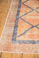 Vintage distressed Oushak runner showcasing worn raspberry-beige tones and geometric pattern.