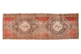 Distressed Oushak runner with interconnected stepped geometric medallions in faded red and charcoal.