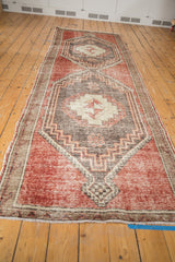 Cherry red distressed Oushak rug end, with narrow border, fringe, and geometric medallion.