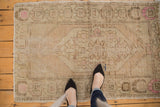 Distressed Oushak rug featuring a diamond motif in beige, blush, and pale brown.