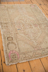 Vintage distressed Oushak rug corner, showing textured pile with pale pink and beige geometric motifs.