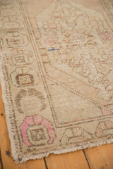 Distressed Oushak rug's muted beige and pale pink tones with visible knot heads.