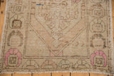 Distressed vintage Oushak rug corner showing even wear, pale pink hues, and original selvage.